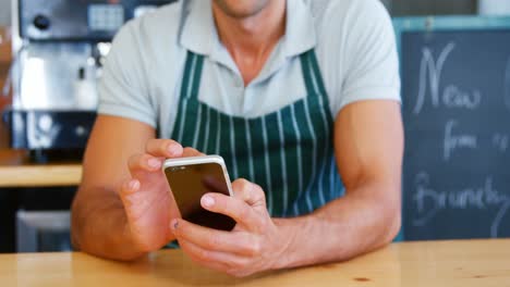 Porträt-Eines-Kellners,-Der-Sein-Smartphone-Auf-Der-Theke-Benutzt