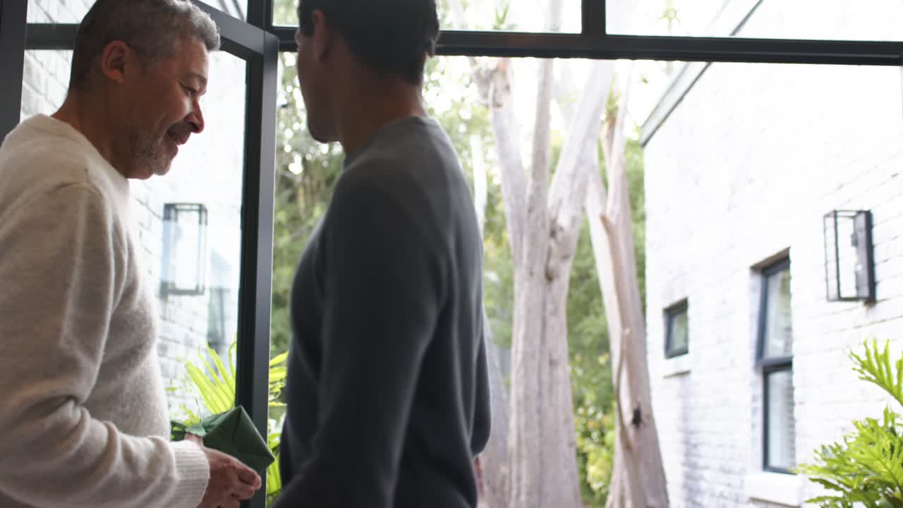Family arriving at home glass-paneled doorway chatting while carrying wrapped gifts for gathering