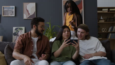 diverse group of friends engaged with a smartphone on a couch