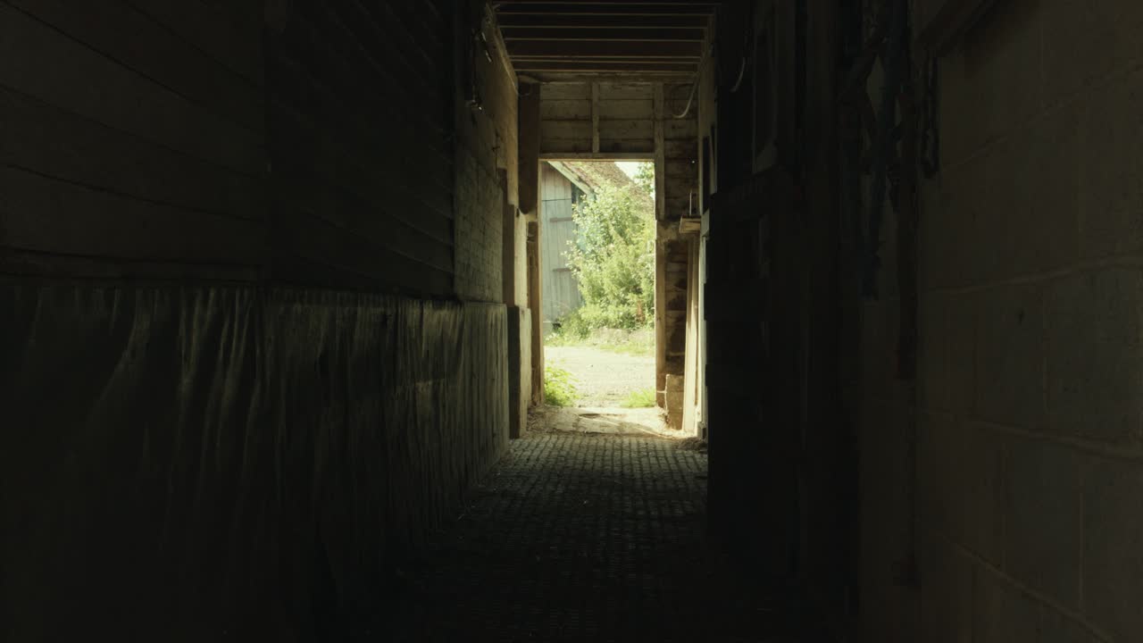 Silhouette Of A Shepherd Closes A Stable Door Then Exits Barn In The Farm. - slider left shot
