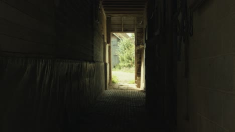 silhouette of a shepherd closes a stable door then exits barn in the farm. - slider left shot