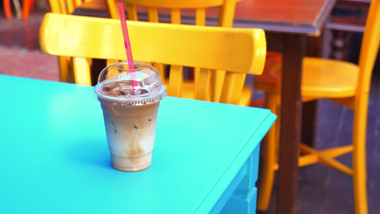 Canlı turkuaz bir kafe masasında ferahlatıcı buzlu kahve.