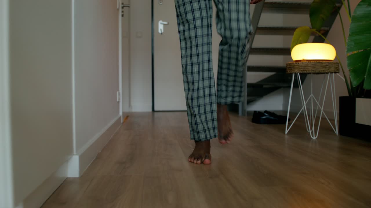 persona caminando descalza en pijama en un interior de la casa