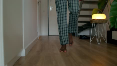 person walking barefoot in pajamas in a home interior