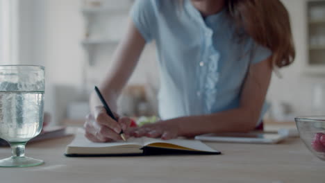 Young-businesswoman-making-notes-in-notebook