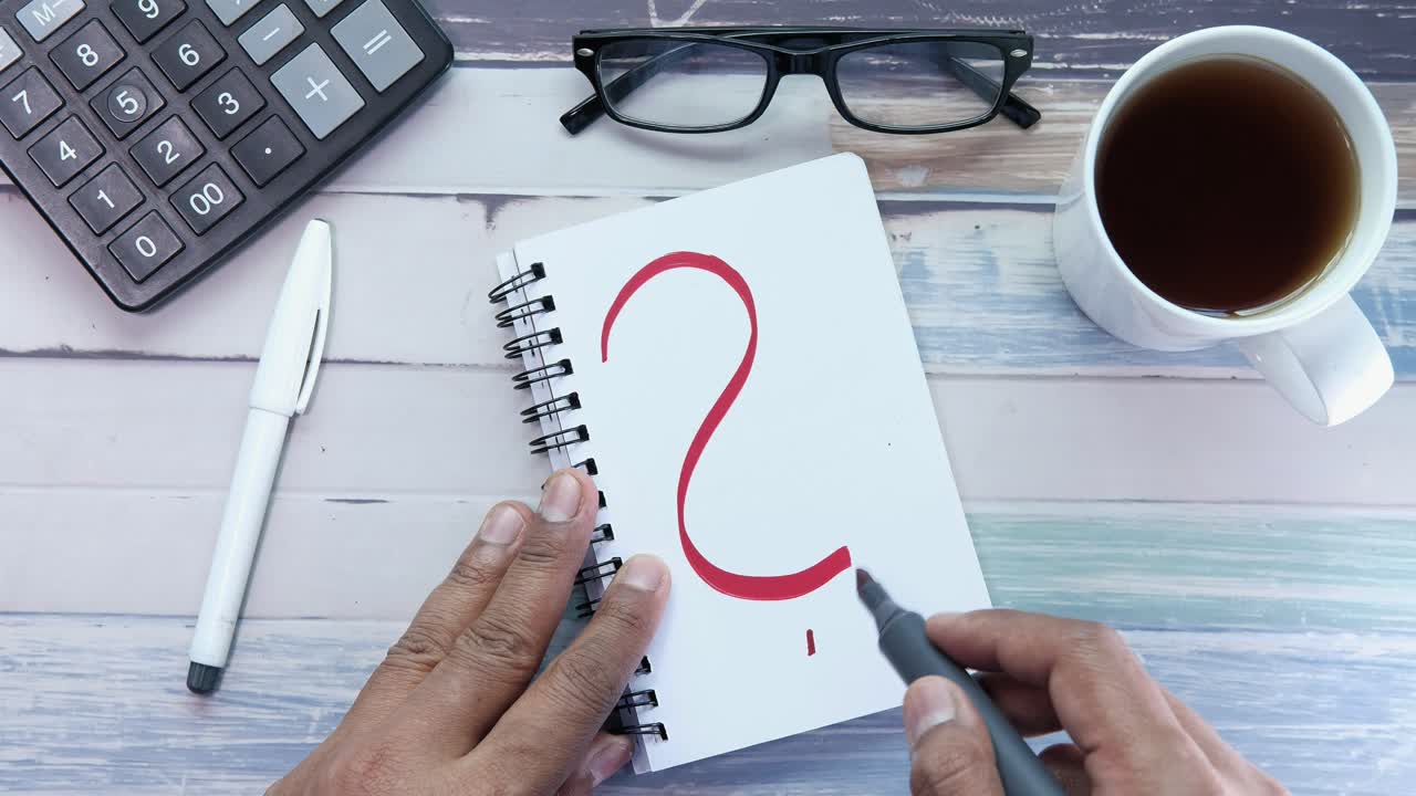 persona que escribe un signo de interrogación en un cuaderno