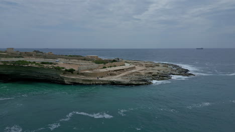 Marsaxlokk,-Malta:-Luftdrohnenaufnahme-In-Vorwärtsbewegung-über-Touristen-Auf-Einem-Tagesausflug-In-Das-Malerische-Fischerdorf-Hofriet-Window,-Marsaxlokk,-Malta-Bei-Tag