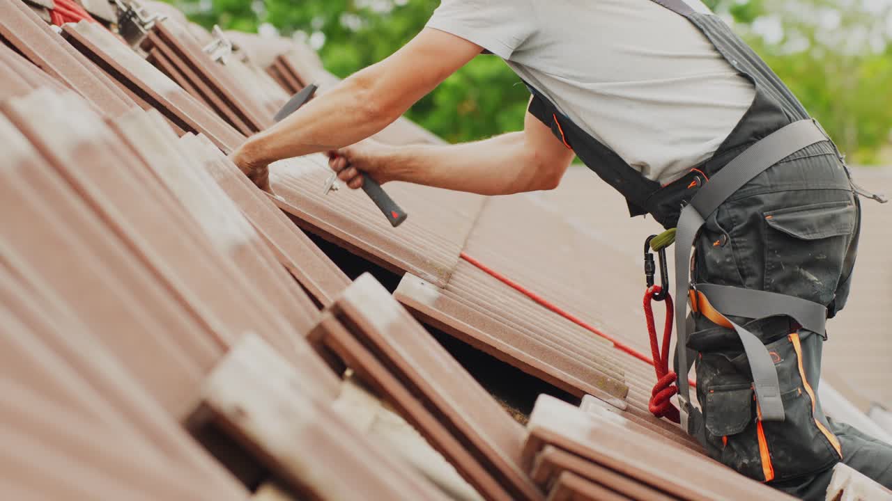 Man working with hammer on top of rooftop, side view