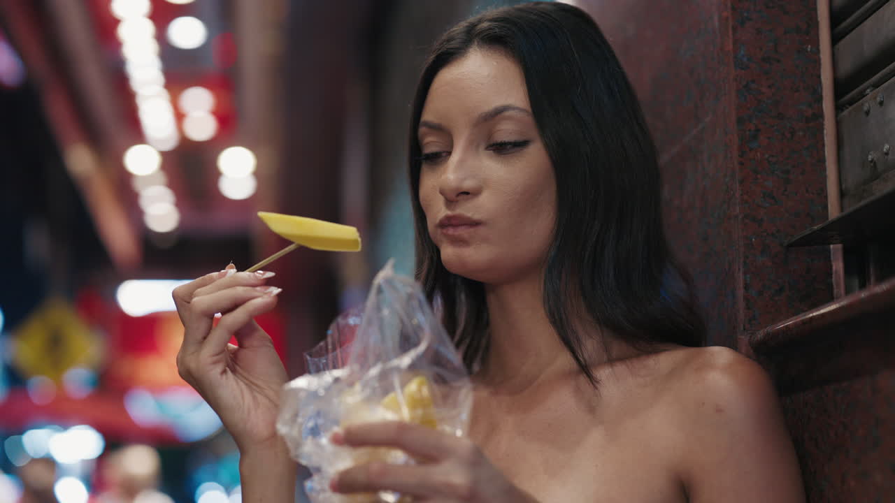 Donna che mangia mango al mercato notturno
