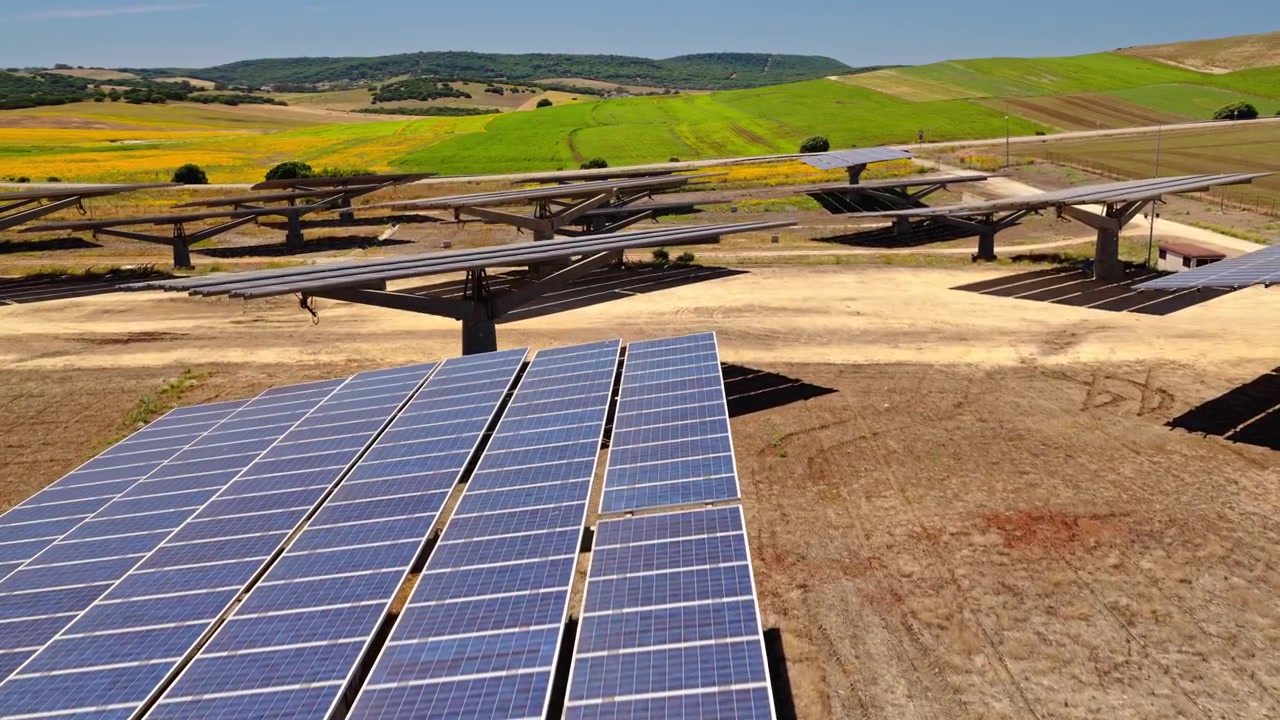 Filmisk droneoptagelse flyver over et stort solcelleanlæg med fotovoltaiske paneler, der genererer ren, vedvarende elektricitet. Bæredygtig energiinfrastruktur, der understøtter den globale energiovergang.