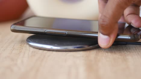 hand placing a mobile phone on a wireless charging pad