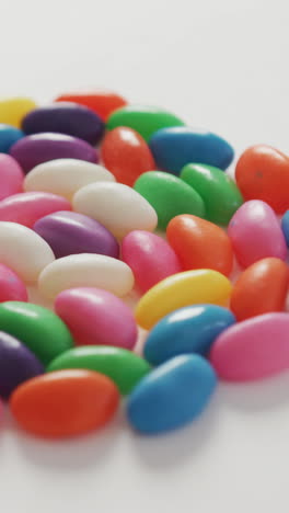 video of close up of multi coloured sweets forming circle over white background