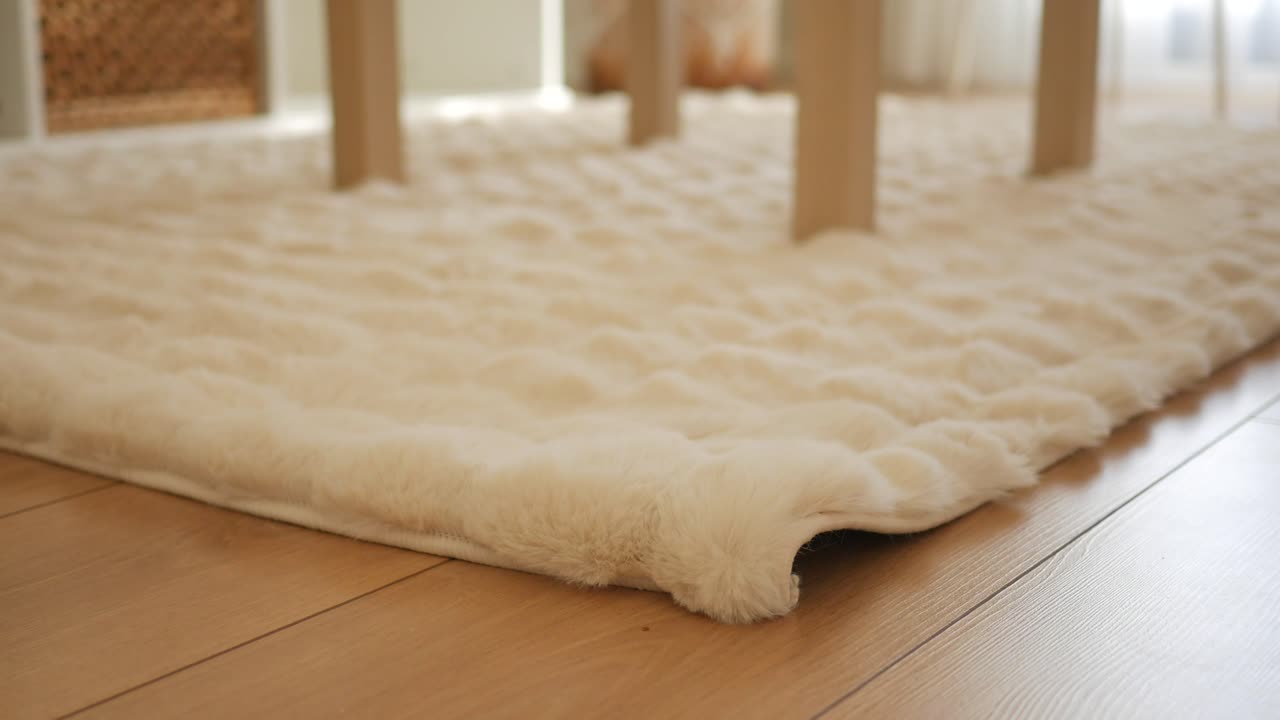 Primo piano di un soffice tappeto bianco su un pavimento in legno.