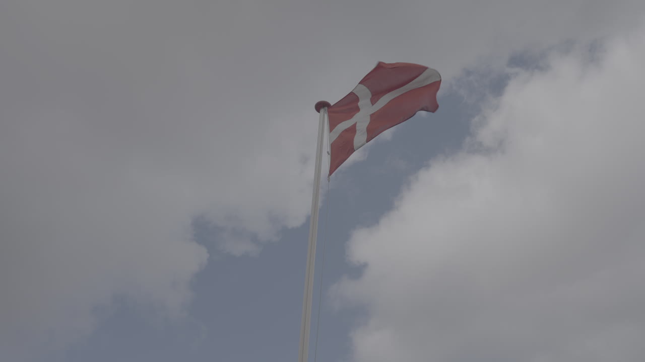 Dansk flag vajende i vinden i slowmotion i København, Danmark på en overskyet dag LOG.