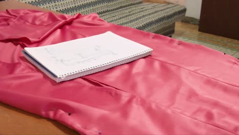 close up of a latin seamstress marking a dress with a white chalk an a curve ruler