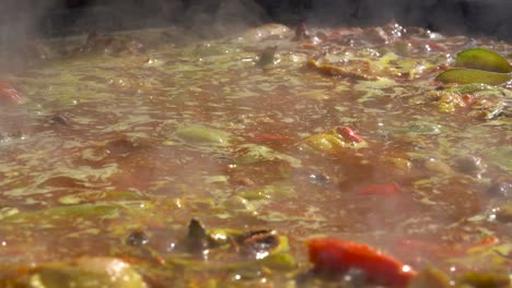 cook moves a valencian paella with the shovel while the broth boils