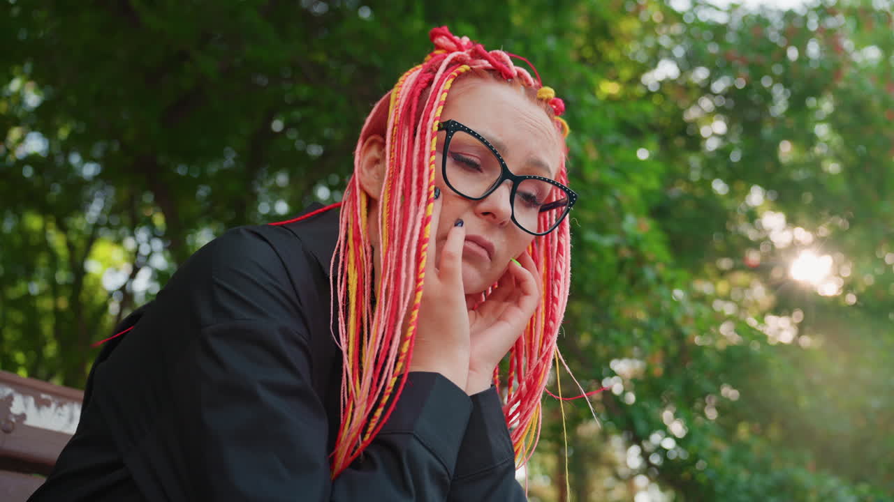 평화로운 공원에 앉아 휴식을 취하는 편안한 여성, 밝은 드레드락 헤어스타일을 한 여성이 평화롭게 쉬고 있는 고요한 장면, 야외에서 조용한 시간을 즐기는 밝은 머리색의 여성을 담은 평온한 인물 사진