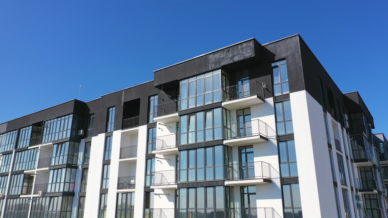 Beautiful design of multistorey building. New apartment with balconies against blue sky. Exterior of residential building.