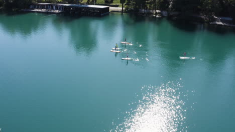 scenic view of people standup paddleboarding during summer at lake bled in slovenia