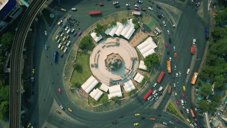 4K-Cinematic-urban-drone-footage-of-an-aerial-panoramic-smoky-view-of-the-Victory-Monument-roundabout-in-the-middle-of-downtown-Bangkok,-Thailand-during-burning-season