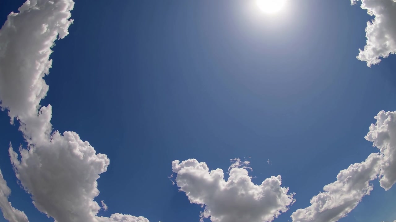 Sole splendente in un cielo azzurro limpido con nuvole bianche e soffici