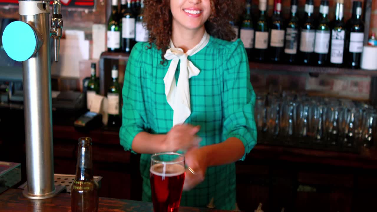 camarera vertiendo cerveza en un vaso en el mostrador de la barra