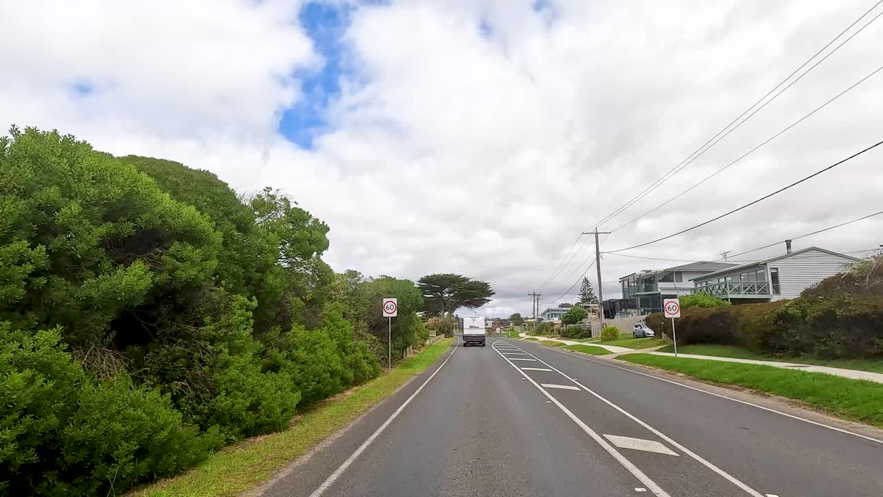 A serene drive along Great Ocean Road with lush greenery, clear skies, and coastal views captured in daylight
