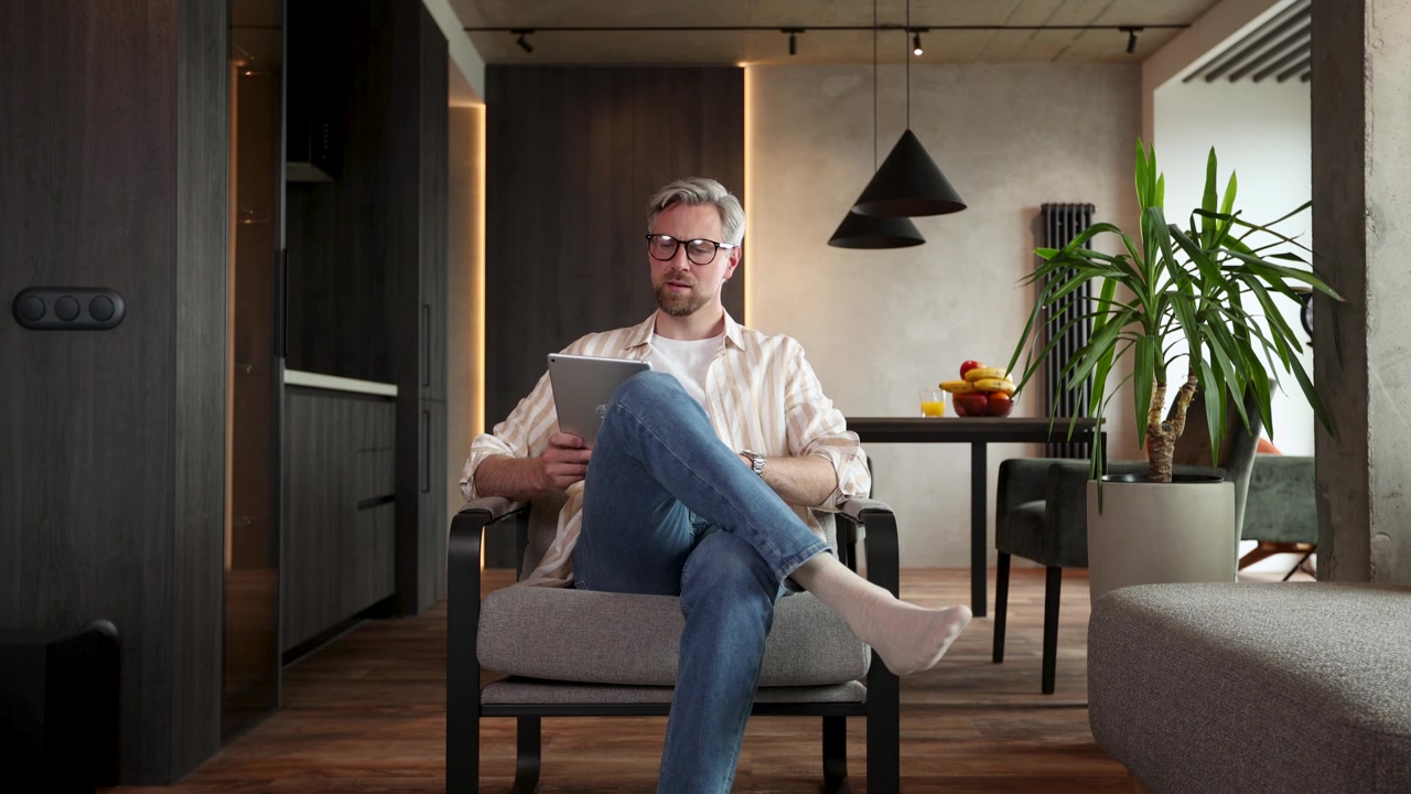 Man Relaxing on Armchair and Using Digital Tablet at Home