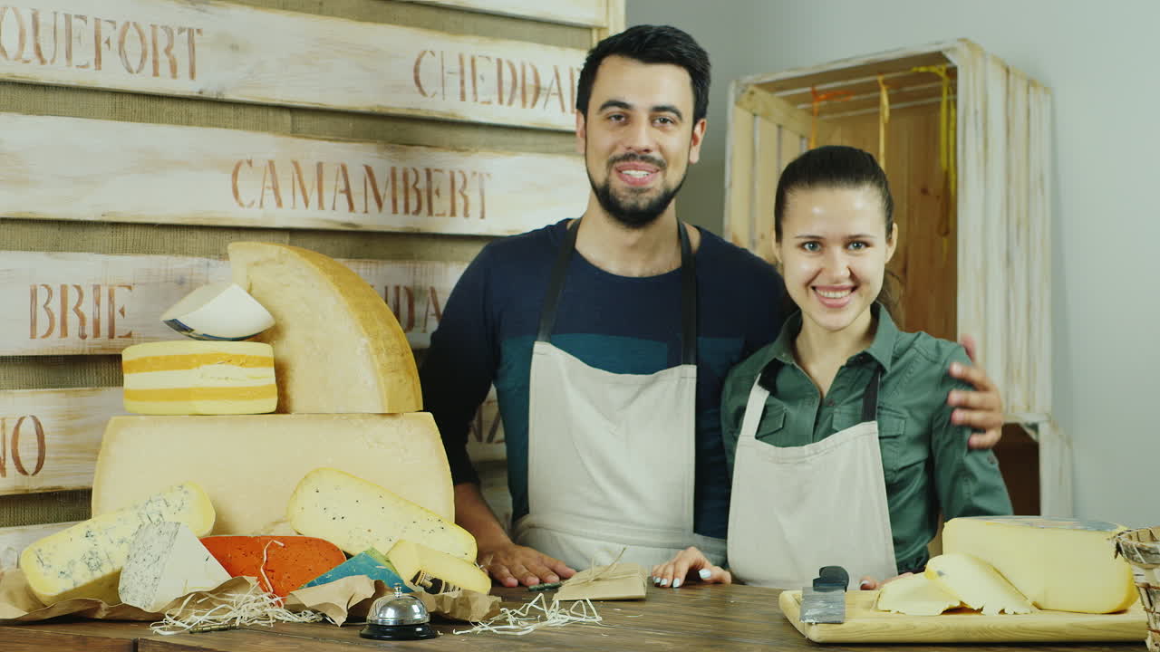 pequeña empresa exitosa el hombre y la mujer detrás del mostrador de la tienda de quesos mirando c