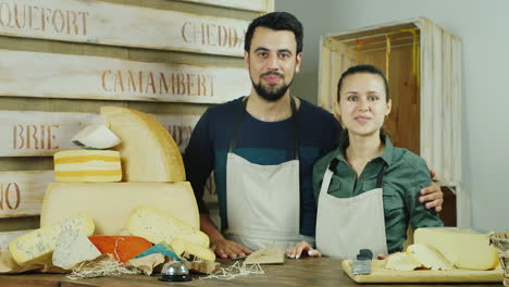 successful small business the man and the woman behind the counter of the store cheeses looking at c