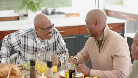 african american senior father and son talking and laughing at thanksgiving dinner , slow motion