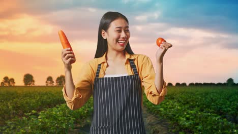 woman holding carrot and tomato in a field at sunset