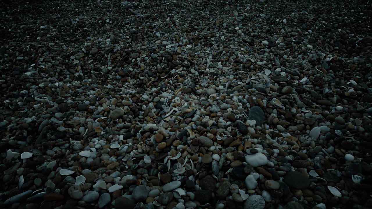 해가 지는 동안 해변의 비석을 가로질러 움직입니다.