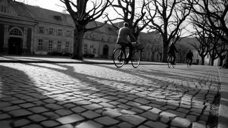 person cycling on a cobblestone street in black and white