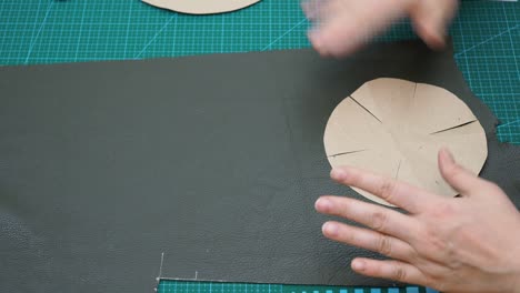 craftsman draws cutting pattern of the bottom of pouch using paper pattern