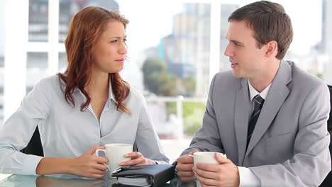 Serious-colleagues-talking-together-while-drinking-coffee