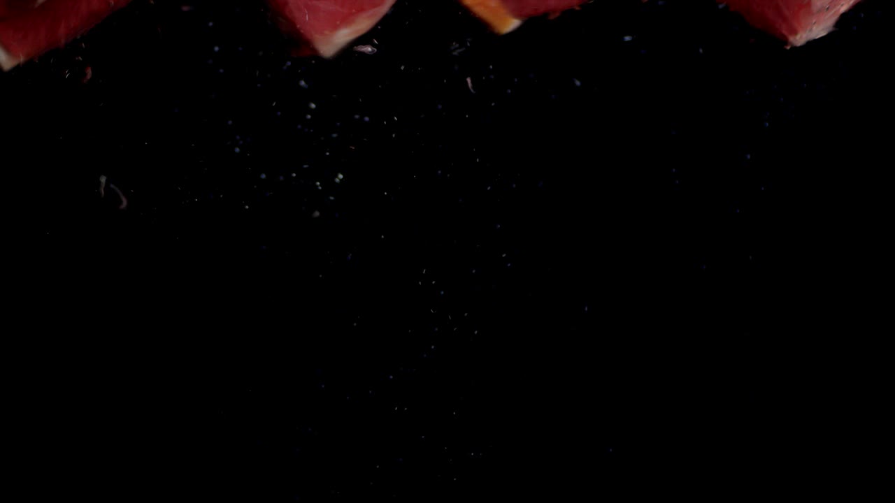 las secciones de pomelo caen en el agua con burbujas de aire.