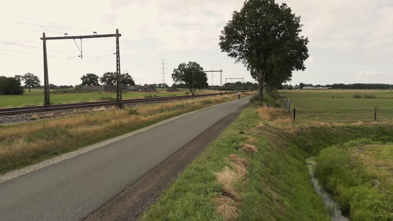 열차 트랙 의 시골 도로에서 자전거 타는 사람