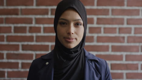 Retrato-Joven-Musulmana-Independiente-Gira-La-Cabeza-Luciendo-Feliz-Usando-Velo-Hijab-En-Pared-De-Ladrillo-Fondo-Cultura-Islam-Cámara-Lenta