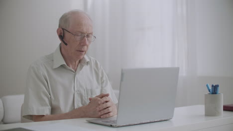 Un-Anciano-Está-Usando-Una-Videollamada-En-Un-Portátil-Sentado-En-Casa-Para-Comunicarse-Con-Colegas-Que-Se-Aíslan-Y-Trabajan-A-Distancia