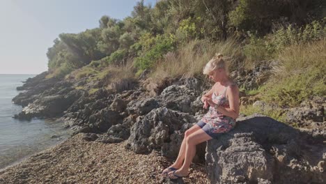 woman relaxing on rocky beach by the sea