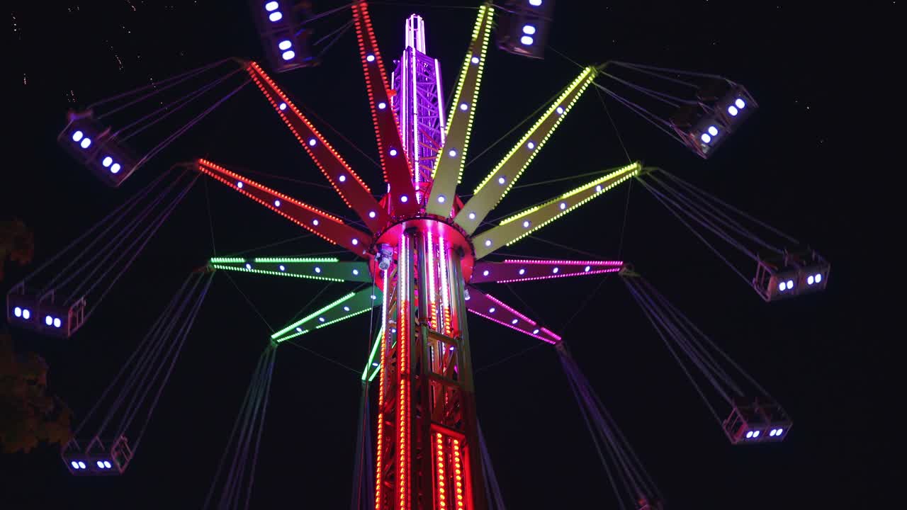 4K Tall bright colourful merry-go-round in amusement park at night