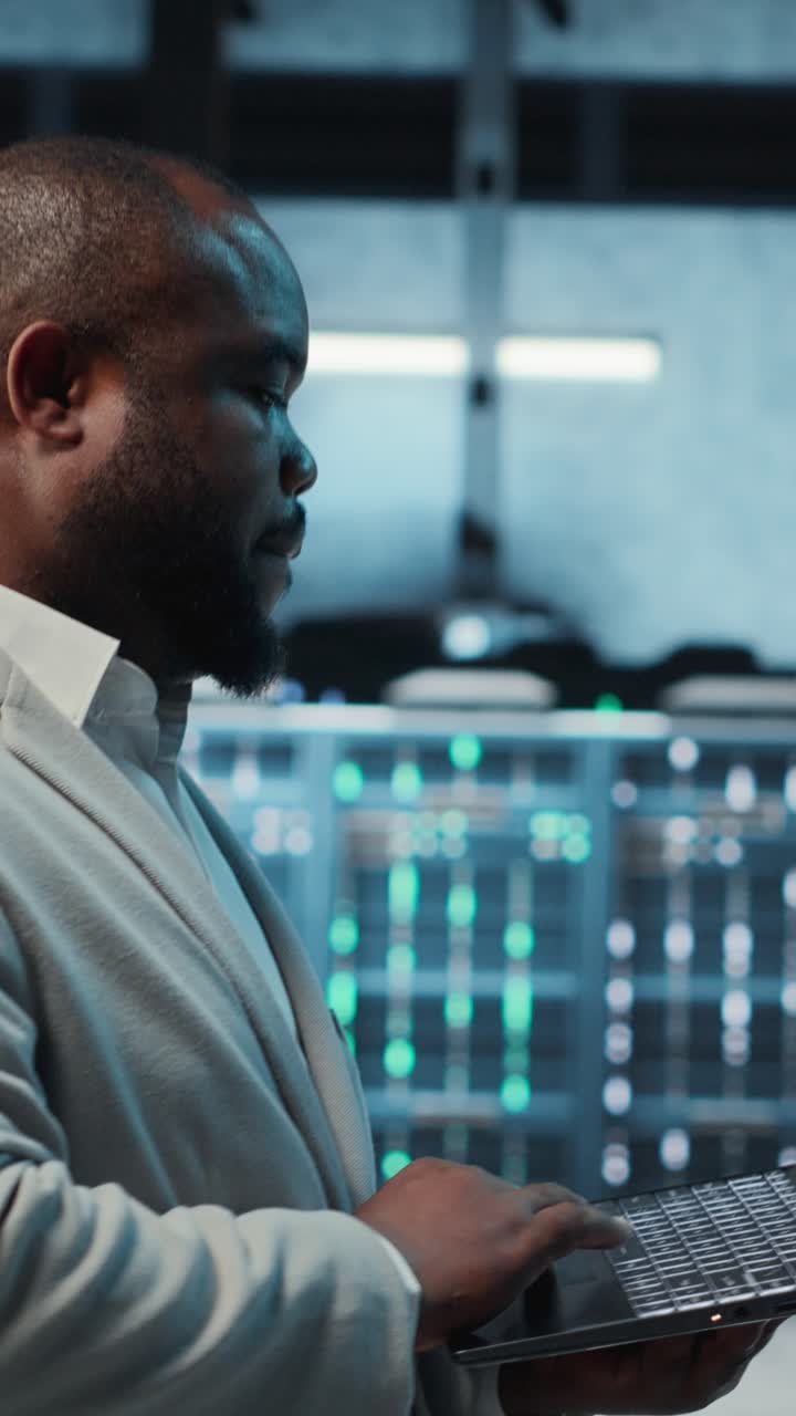 Vertical video Manager overseeing server room, walking with laptop, troubleshooting hardware