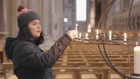 woman lighting a votive candle at the linkoping cathedral in sweden