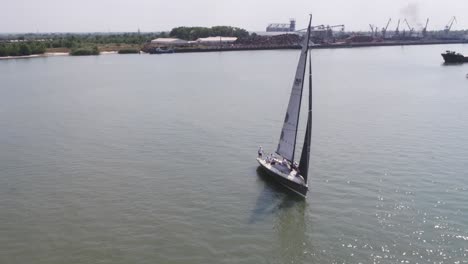 sailing yacht on a river with industrial port background