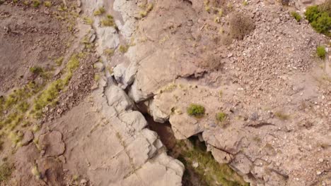 Deep-old-river-bed-valley-in-desert-landscape-of-Tenerife,-aerial-top-down