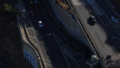 Drohnenaufnahme-Des-Verkehrs-In-Los-Angeles,-Der-Auf-Einer-Brücke-Und-Aus-Einem-Tunnel-Herausfährt