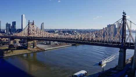 east river amidst buildings in city, drone flying backward from skyline
