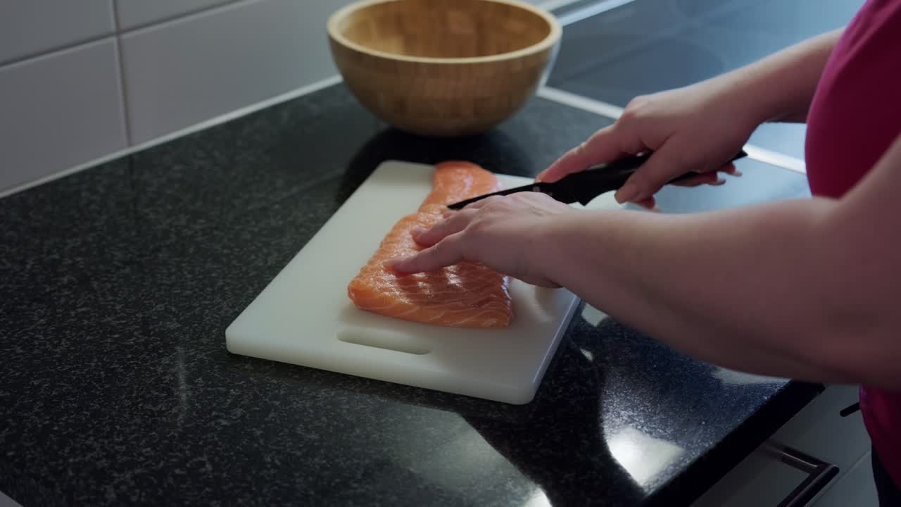 Woman hands cutting raw salmon in slices, interior