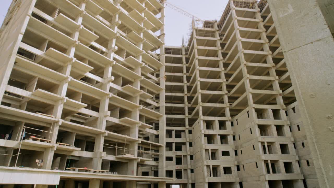 Concrete apartment structures in mid-construction phase amidst urban development in Karachi.